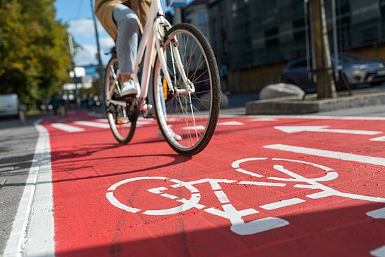 woman cycling along red bike lane road in city