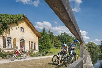 Eine Familie macht Rast am Schleusenhäuschen. Der Mann mit Junge schauen interessiert den Kanal an. Die Frau mit Mädchen stehen am Häuschen. Das Schleusenhäuschen ist auf der linken Seite etwas vom Effeu eingewachsen.